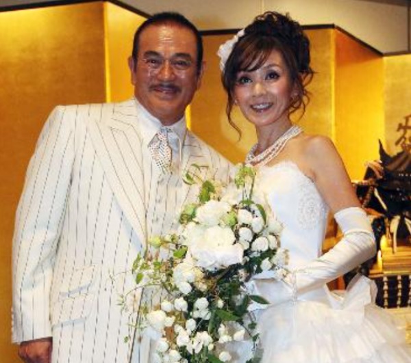 千葉真一とタマミチバが結婚披露宴でドレスを着て花束を持っている